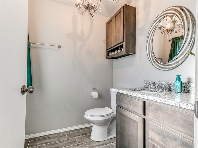 bathroom with an inviting chandelier, vanity, and toilet