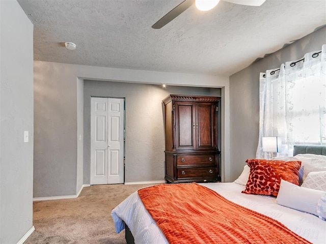 bedroom with ceiling fan, light colored carpet, and a textured ceiling