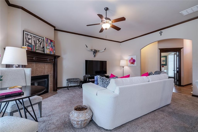 carpeted living room featuring ornamental molding, ceiling fan, and a fireplace