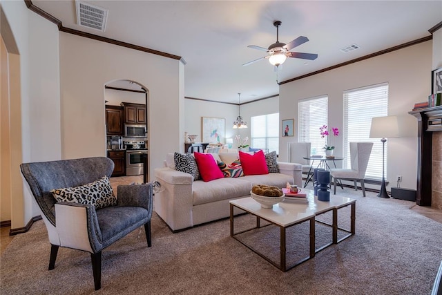 carpeted living room with ceiling fan with notable chandelier and ornamental molding