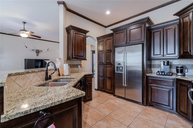 kitchen with dark brown cabinetry, sink, light stone counters, and stainless steel built in fridge