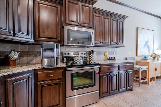 kitchen featuring light tile patterned flooring, tasteful backsplash, crown molding, light stone counters, and stainless steel appliances