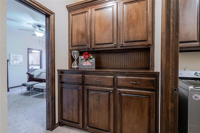 interior space with ceiling fan, dark brown cabinetry, washer / dryer, and light carpet