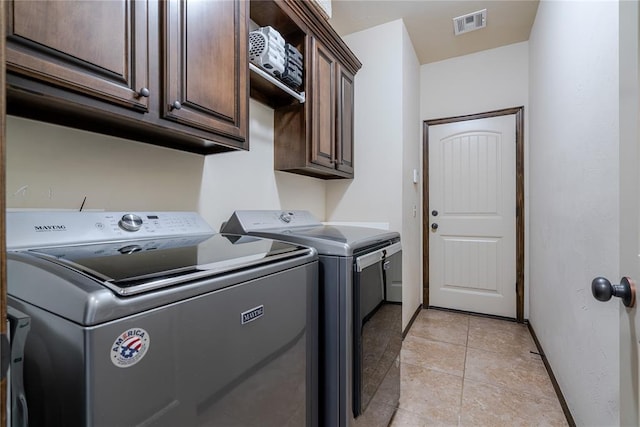 laundry room with light tile patterned flooring, cabinets, and separate washer and dryer