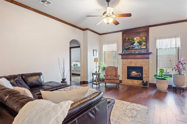 living room with crown molding, plenty of natural light, a tile fireplace, and dark hardwood / wood-style floors