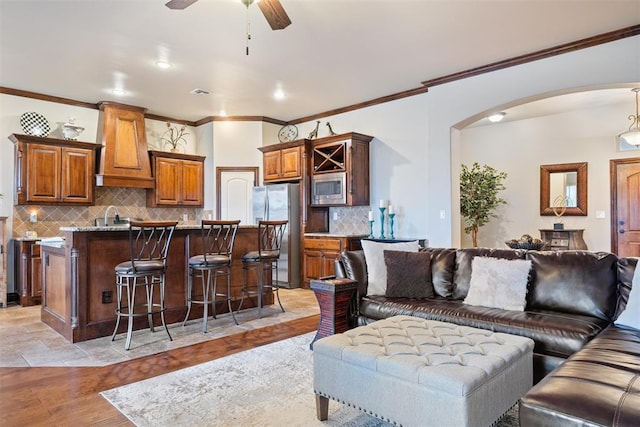 living room with crown molding, sink, ceiling fan, and light hardwood / wood-style floors