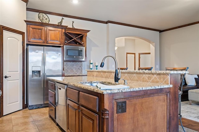 kitchen featuring sink, a breakfast bar area, stainless steel appliances, a center island with sink, and decorative backsplash