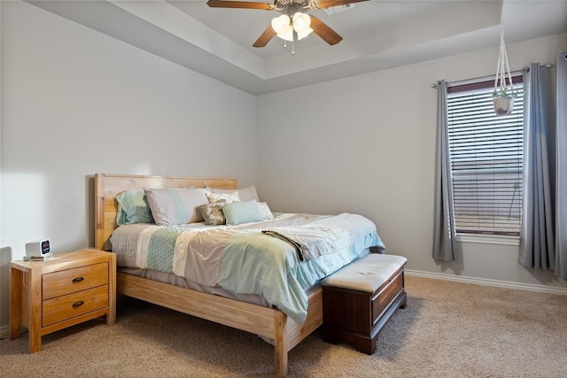 carpeted bedroom featuring ceiling fan and a tray ceiling