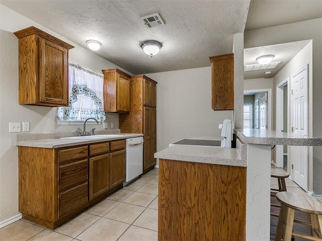 kitchen with a breakfast bar, dishwasher, sink, and light tile patterned floors