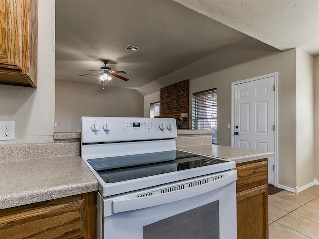 kitchen featuring lofted ceiling, light tile patterned floors, electric range, and ceiling fan