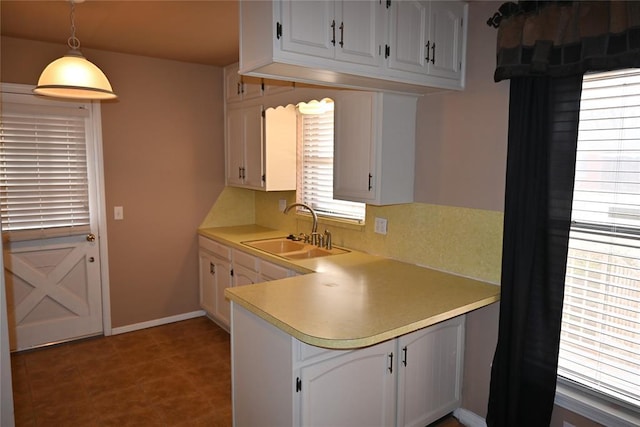 kitchen with backsplash, decorative light fixtures, sink, and white cabinets