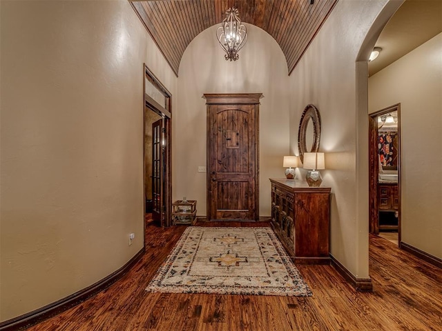 entryway with lofted ceiling, an inviting chandelier, and dark hardwood / wood-style flooring