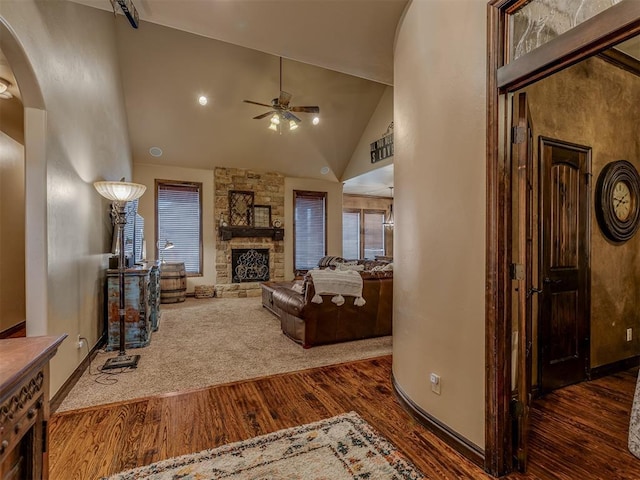 living room featuring dark hardwood / wood-style flooring, a fireplace, high vaulted ceiling, and ceiling fan