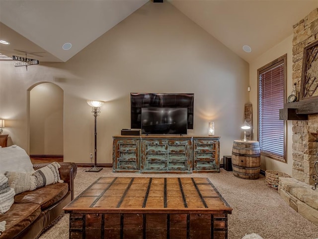 living room featuring a stone fireplace, high vaulted ceiling, and light carpet