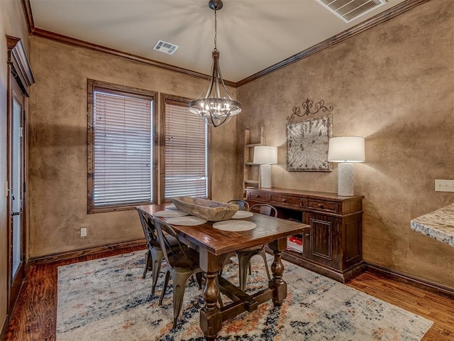 dining room featuring crown molding, dark hardwood / wood-style flooring, and a chandelier