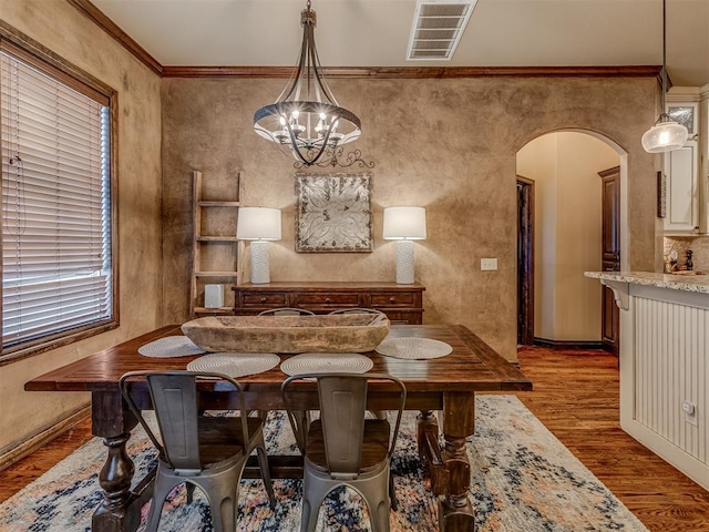 dining area featuring hardwood / wood-style flooring, ornamental molding, and a chandelier