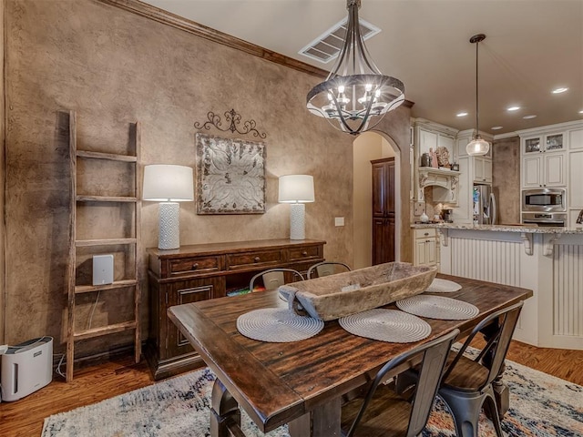 dining room featuring crown molding, hardwood / wood-style floors, and a chandelier