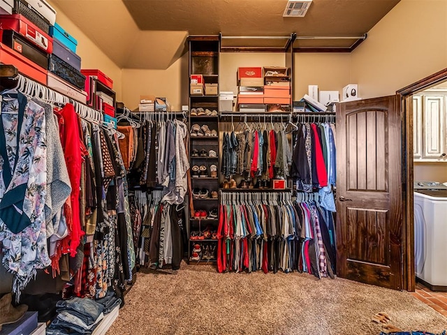 walk in closet with washer / clothes dryer and light carpet