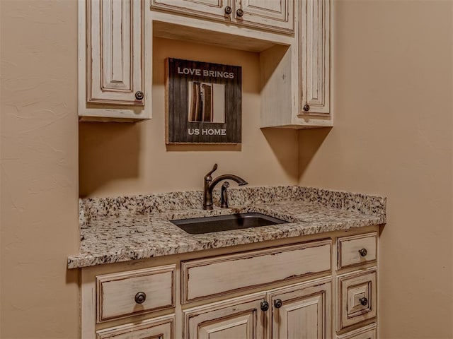 kitchen with sink, light stone countertops, and cream cabinetry