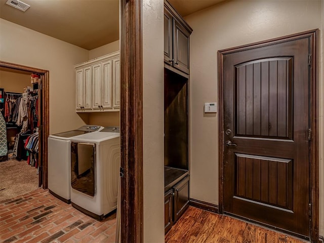 clothes washing area featuring cabinets and washer and dryer