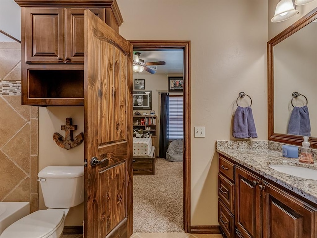 bathroom featuring vanity, a bath, and toilet