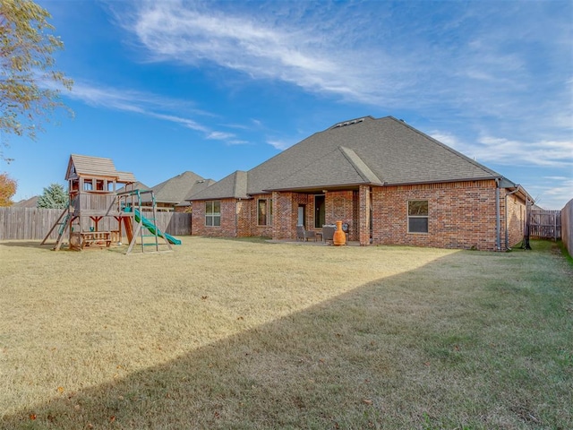 rear view of property featuring a yard and a playground