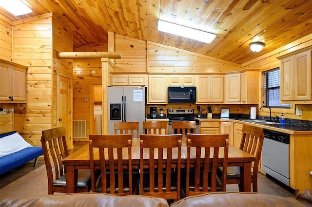 kitchen with stainless steel appliances, sink, light brown cabinetry, and wood walls