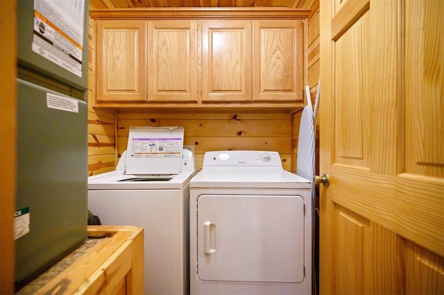 washroom with cabinets, wooden walls, and independent washer and dryer