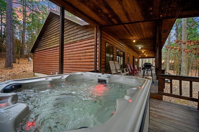 deck at dusk featuring a hot tub