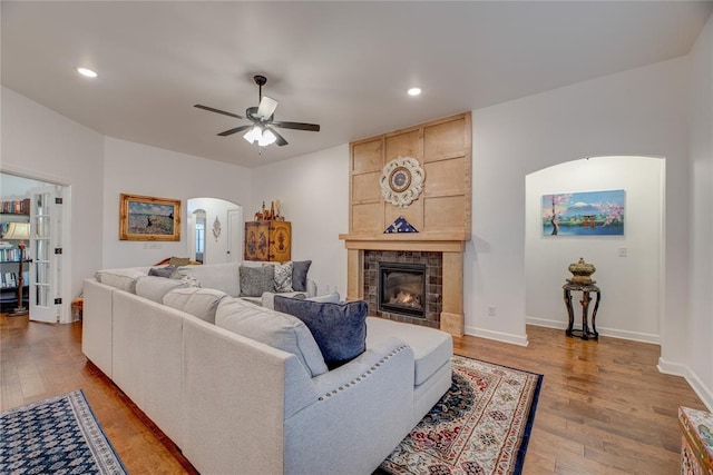 living room with ceiling fan, a fireplace, and light hardwood / wood-style floors