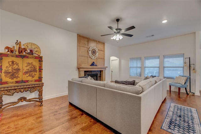 living room with ceiling fan, a fireplace, and light hardwood / wood-style floors