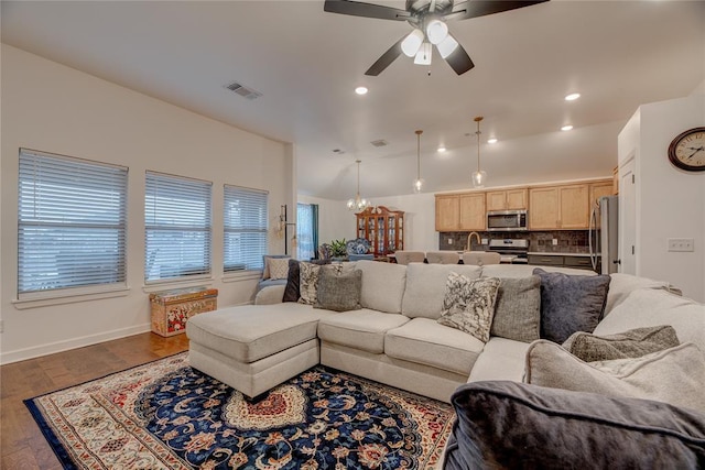 living room with sink, ceiling fan with notable chandelier, wood-type flooring, and vaulted ceiling