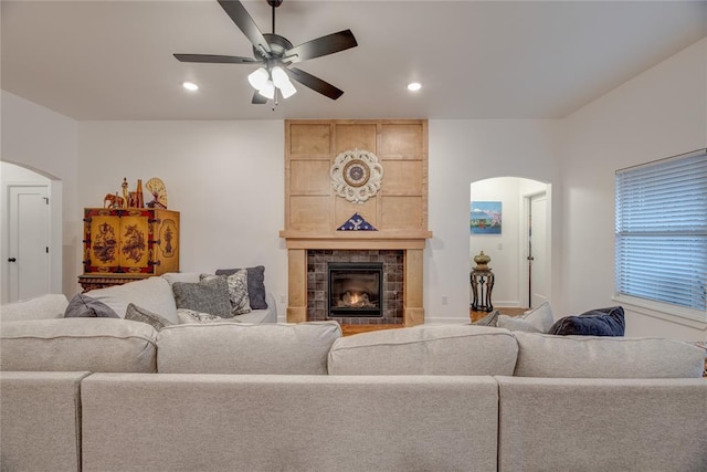 living room featuring a tiled fireplace and ceiling fan