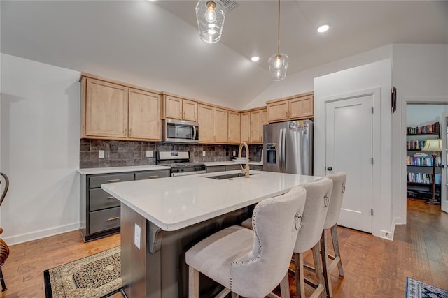 kitchen featuring light brown cabinetry, sink, a center island with sink, appliances with stainless steel finishes, and pendant lighting