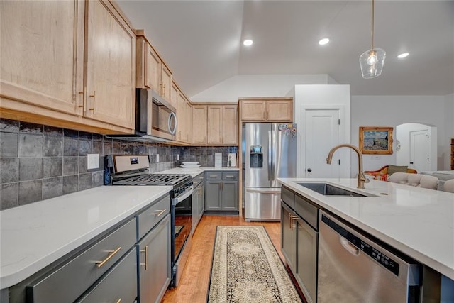 kitchen with gray cabinets, decorative light fixtures, sink, light stone counters, and stainless steel appliances