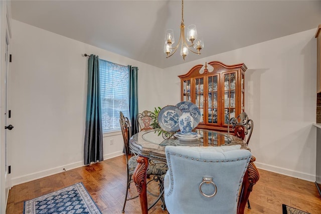 dining room with an inviting chandelier, lofted ceiling, and light hardwood / wood-style flooring