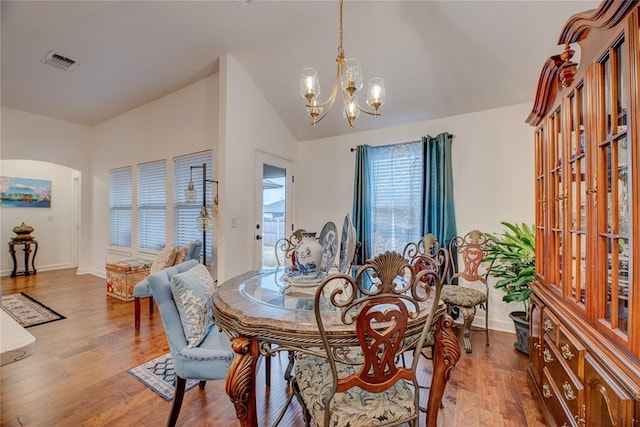 dining space with hardwood / wood-style flooring, vaulted ceiling, and a chandelier