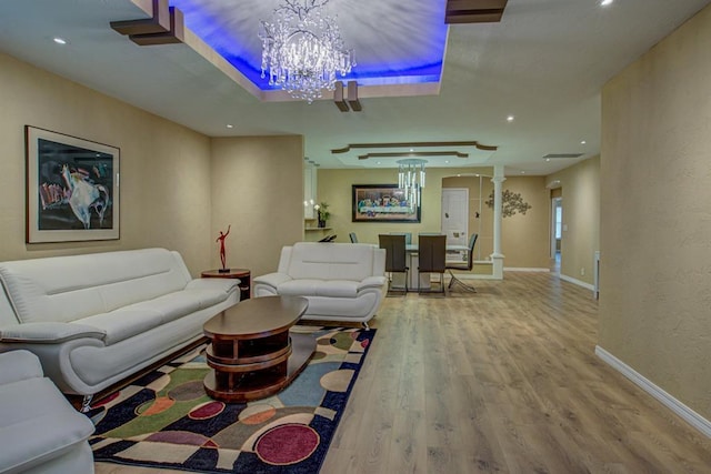 living room with hardwood / wood-style flooring, an inviting chandelier, and decorative columns