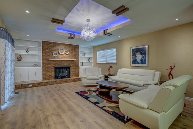 living room featuring wood-type flooring, a brick fireplace, a chandelier, and built in features