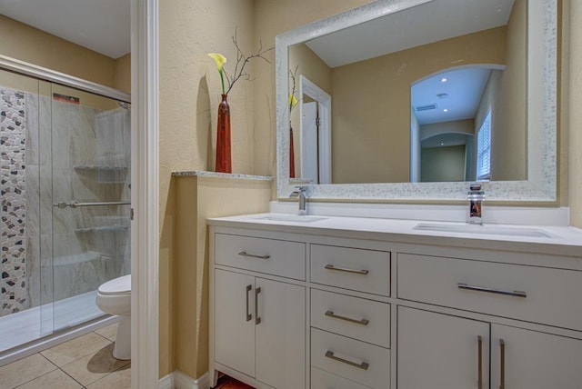 bathroom with tile patterned floors, vanity, toilet, and a shower with door