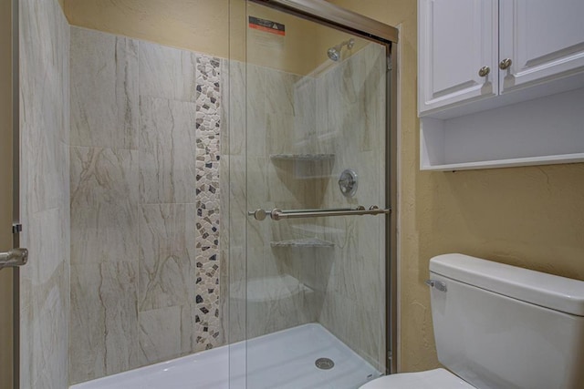 bathroom featuring a shower with shower door and toilet