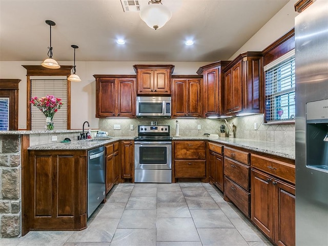 kitchen featuring appliances with stainless steel finishes, decorative backsplash, light stone counters, and decorative light fixtures