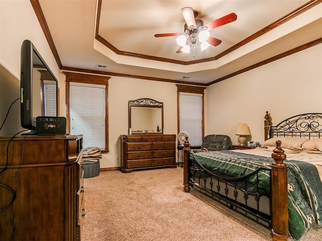 carpeted bedroom with a raised ceiling, crown molding, and ceiling fan