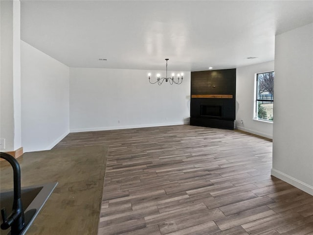 unfurnished living room featuring hardwood / wood-style floors, a notable chandelier, and a fireplace