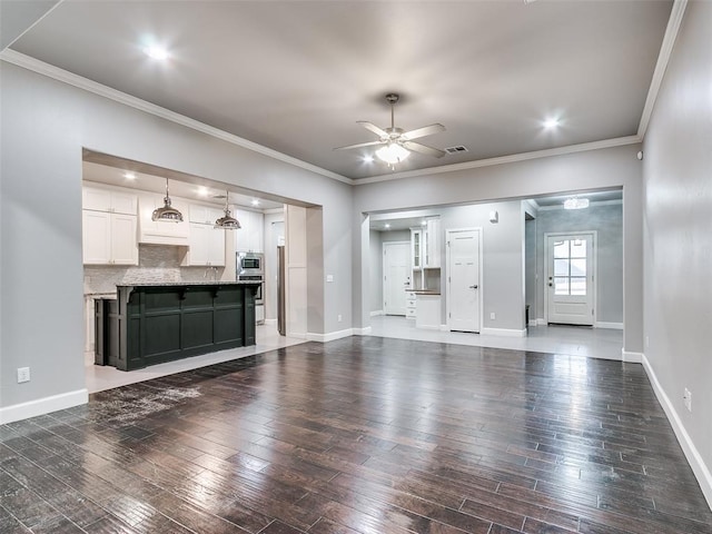 unfurnished living room with dark wood-type flooring, ceiling fan, and ornamental molding