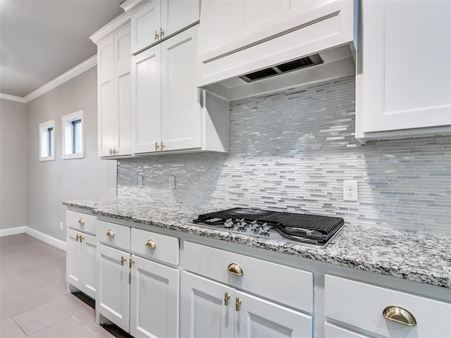 kitchen featuring crown molding, white cabinetry, tasteful backsplash, custom range hood, and stainless steel gas stovetop