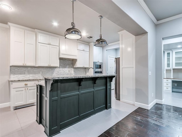 kitchen featuring crown molding, a kitchen island with sink, stainless steel appliances, light stone countertops, and white cabinets