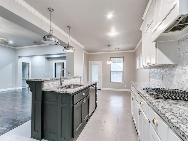 kitchen with white cabinetry, sink, decorative light fixtures, and a kitchen island with sink