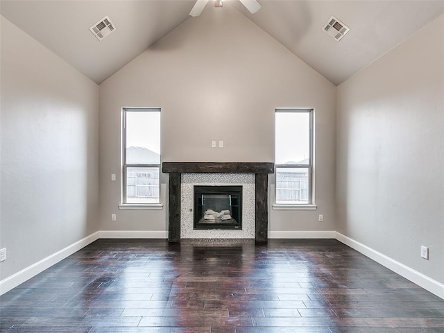 unfurnished living room with dark wood-type flooring, ceiling fan, a tiled fireplace, and high vaulted ceiling