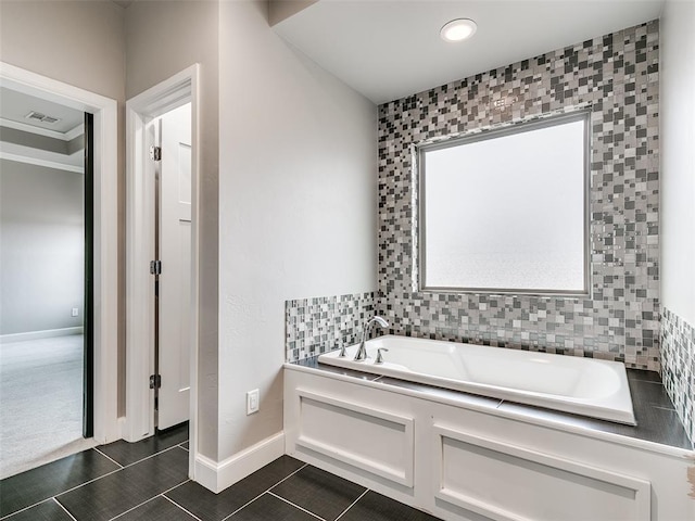 bathroom featuring backsplash, tile patterned floors, and a tub